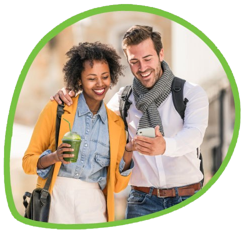 Two friends smiling at a phone while walking downtown